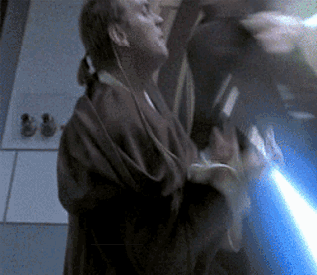 a man in a brown robe is holding a blue lightsaber