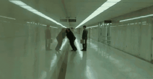 two men are walking down a hallway with a sign above them that says ' emergency exit '