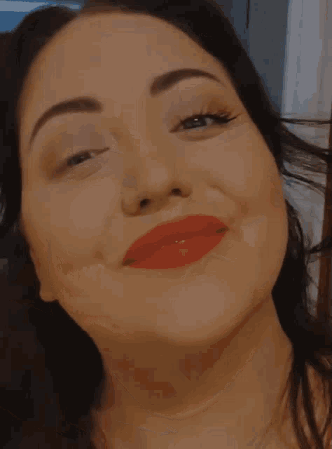 a woman wearing red lipstick and a ring is smiling