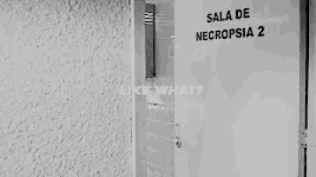 a black and white photo of a woman standing in front of a door that says `` like what ? '' .