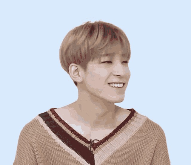 a young man wearing a brown and black striped sweater smiles