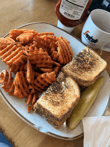 a sandwich and waffle fries on a plate with a cup that says segafredo