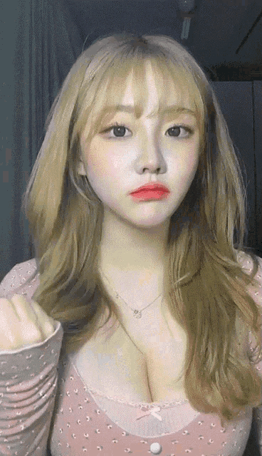 a woman with blonde hair and red lips is wearing a pink top with polka dots