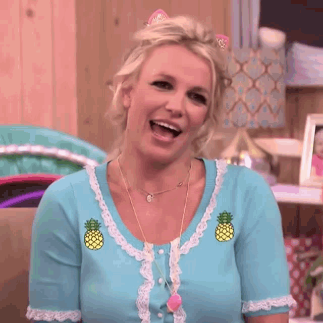 a woman in a blue shirt with pineapples on it is smiling .