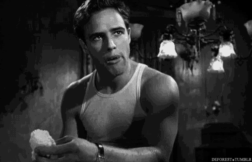 a man in a tank top is holding a piece of cotton candy in his hand in a black and white photo .