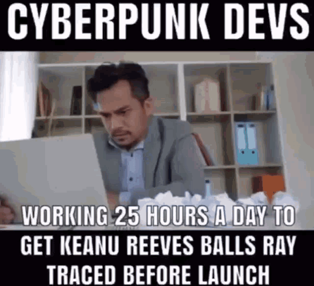 a man in a suit is sitting at a desk looking at a laptop .