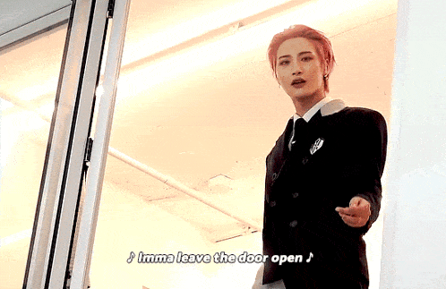 a man in a suit and tie is standing in front of a door and saying imma leave the door open .