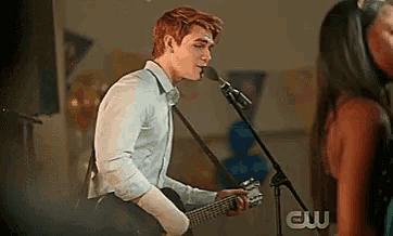 a man is singing into a microphone while playing a guitar on stage .