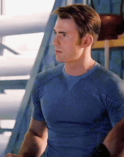 a man in a blue shirt is standing in a room with his hands on his hips