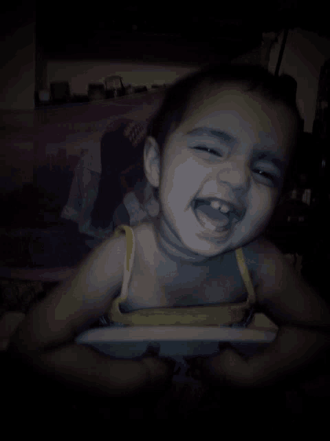 a little girl is smiling with her mouth open in front of a picture of a woman