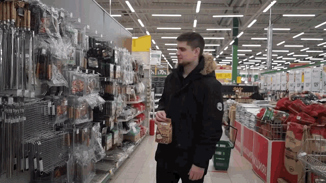 a man in a black jacket holding a bag of food in a store