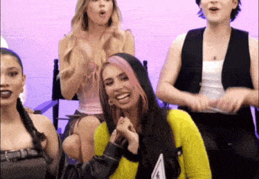 a group of women are sitting in chairs and one of them has pink hair