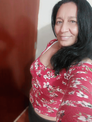 a woman in a red floral top smiles for a picture