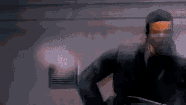 a man in a mask is standing in a dark room holding a piece of paper .