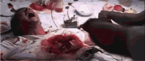 a person is laying on a table with blood on their chest and face .