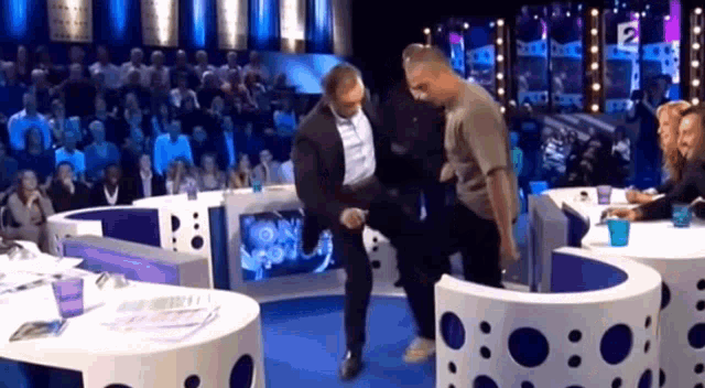 a man in a suit is kicking another man on a stage .