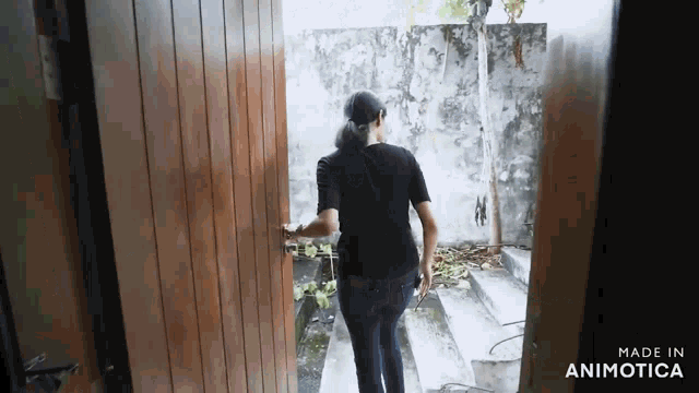 a woman opens a wooden door with the words made in animotica on the bottom