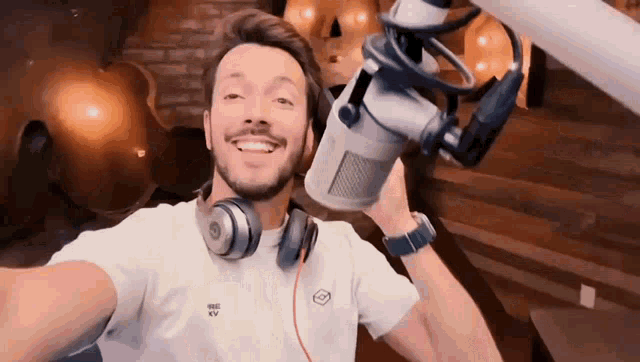 a man wearing headphones is taking a selfie with a microphone in his hand .