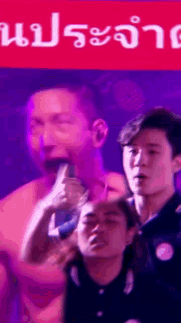 a group of people are standing in front of a sign that says ' ประ จํา '