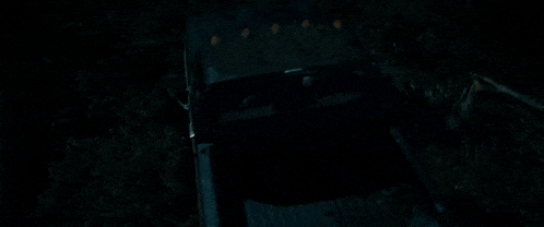a truck is parked in the dark in a dark forest .