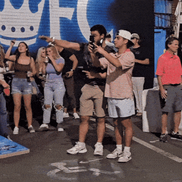a group of people are standing in front of a wall with a crown and the letter t.