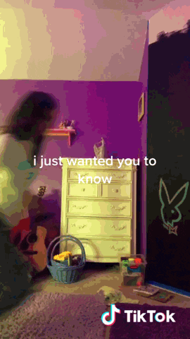 a tiktok video of a girl playing a guitar in a purple room