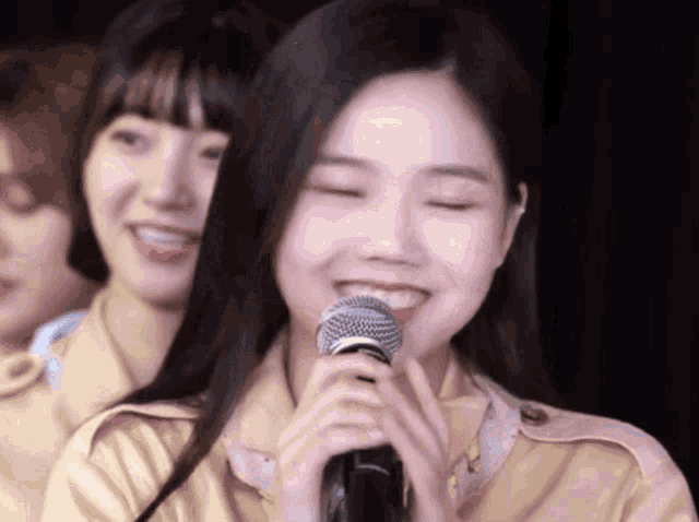 a girl is smiling while holding a microphone in her hand