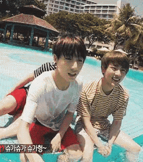 two young boys are sitting in a swimming pool and one of them is wearing a striped shirt .