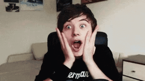 a young man is sitting in a chair with his mouth open and making a surprised face .