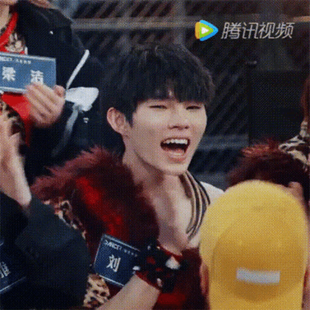 a young man is sitting in a crowd with his mouth open and people clapping .