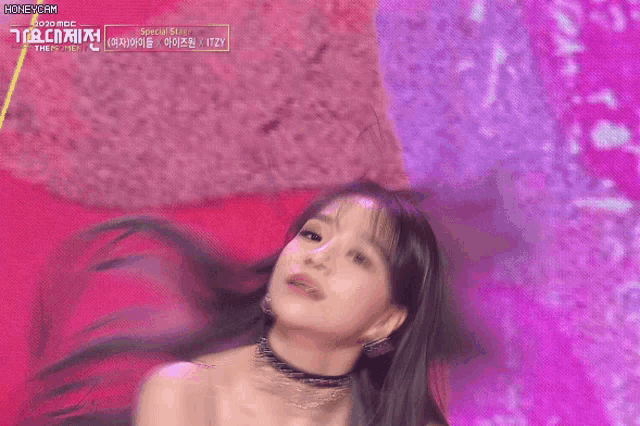 a woman is dancing on a stage in front of a pink background .
