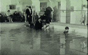 a group of people are standing around a swimming pool in a building .