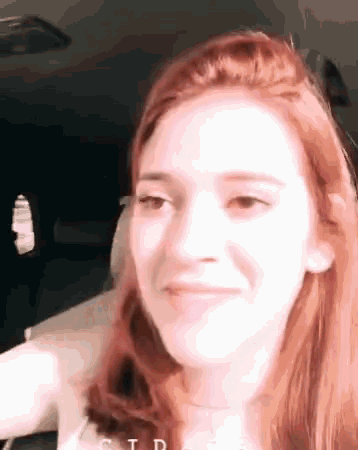 a close up of a woman 's face with red hair making a face .