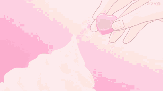 a hand is holding a pink heart above whipped cream