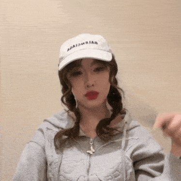 a woman wearing a white hat that says balenciaga