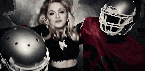 a woman in a black crop top is standing next to a football player in a red uniform .