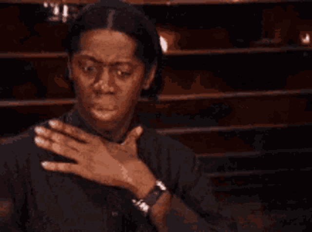 a woman in a black shirt is covering her mouth with her hand .