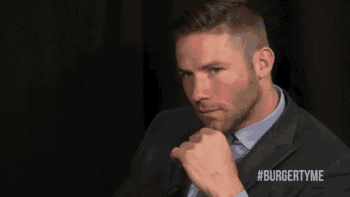 a man in a suit and tie with #burgertyme on his chest