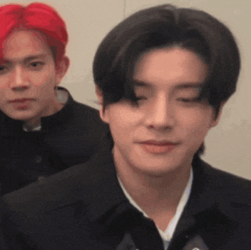 a man with red hair and a man with black hair are standing next to each other and looking at the camera .