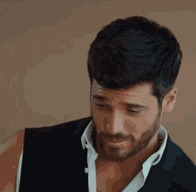 a man with a beard is wearing a black jacket and white shirt