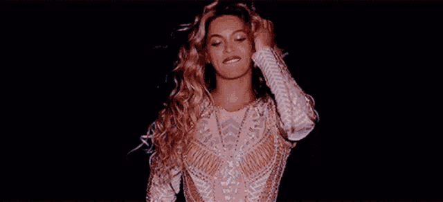 a woman with blonde curly hair is making a funny face while holding her hair .