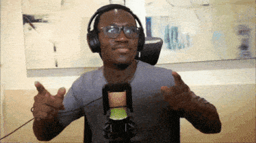 a man wearing headphones and glasses is standing in front of a microphone