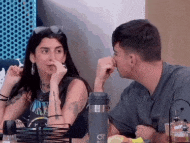 a man and a woman are sitting at a table looking at each other .