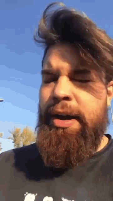 a man with a beard is wearing a black shirt with a picture of a sheep on it