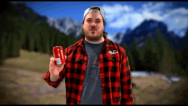 a man in a plaid shirt is holding up a can of coca cola