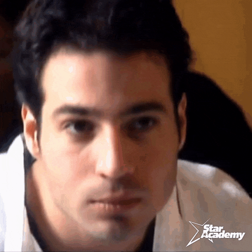 a close up of a man 's face with a star academy logo