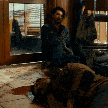 a man sits next to a man laying on the ground