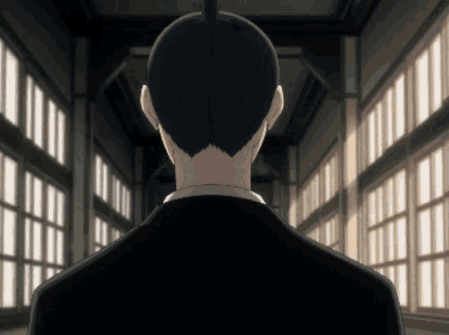a man with a ponytail is standing in a hallway with lots of windows
