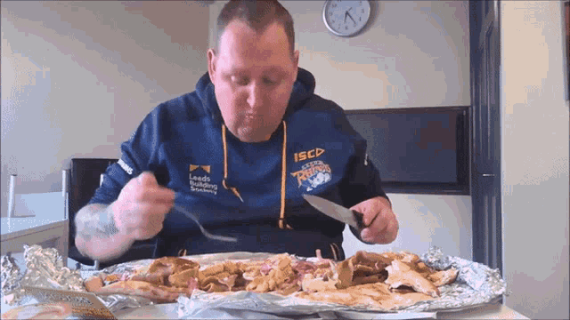 a man wearing a sweatshirt that says iscd eating a pizza