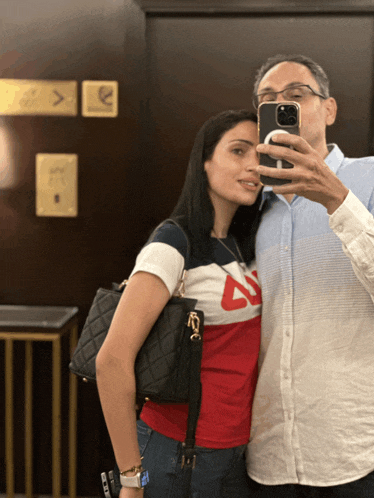 a man taking a selfie with a woman wearing a shirt with the letter a on it